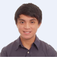 Young person with short black hair, smiling, wearing a dark collared shirt against a pale background.