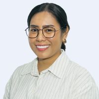 Person with glasses and long dark hair tied back, wearing a striped shirt, smiles at the camera against a plain background.