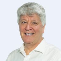 Smiling man with short gray hair wearing a white shirt, in front of a light gray background.